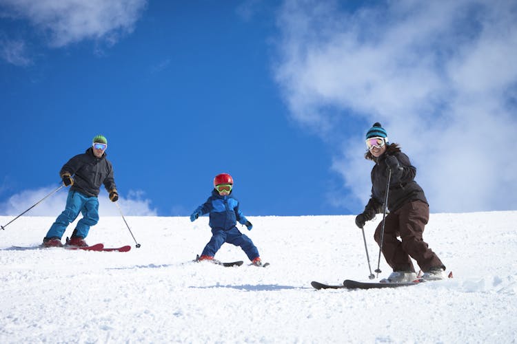 Family with two adults and one child skiing down a piste