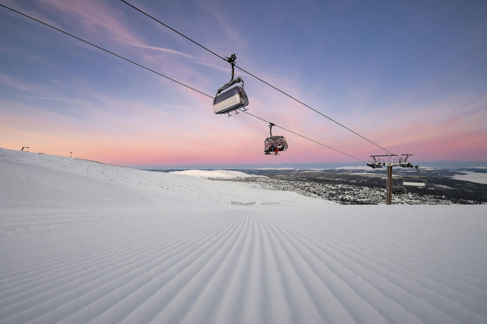 Skiiers being transported to top of mountain on chairlift at sunrise